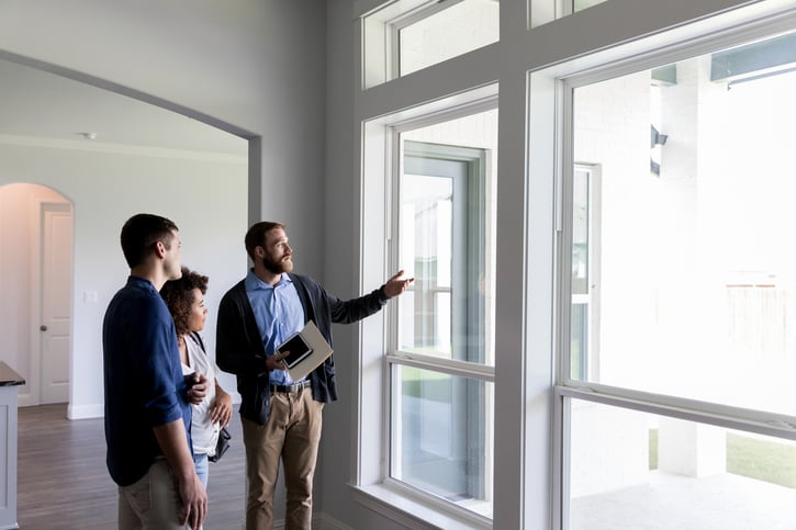 Realtor showing home to man and woman looking out of beautiful new windows