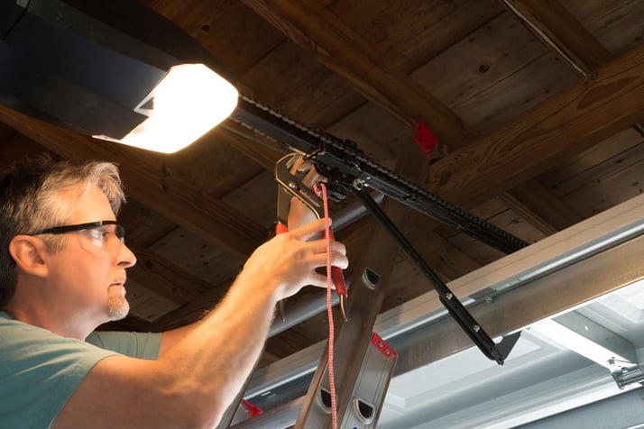 Professional automatic garage door opener repair service technician working closeup Professional automatic garage door opener repair service technician working closeup