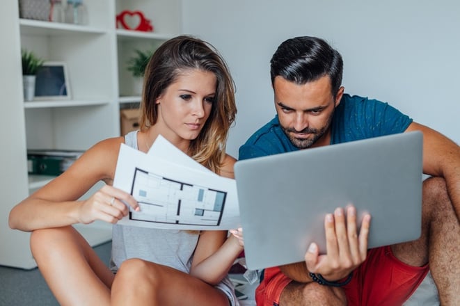 couple looking at at tablet and blueprints thinking about moving into a new apartment
