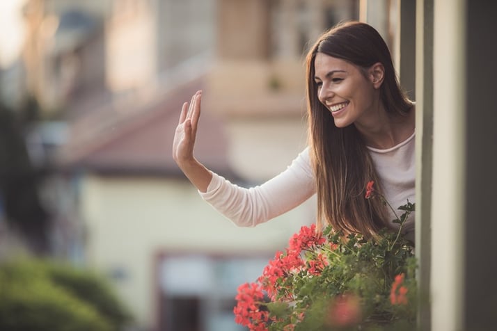 woman waving at neighbor from apartment window