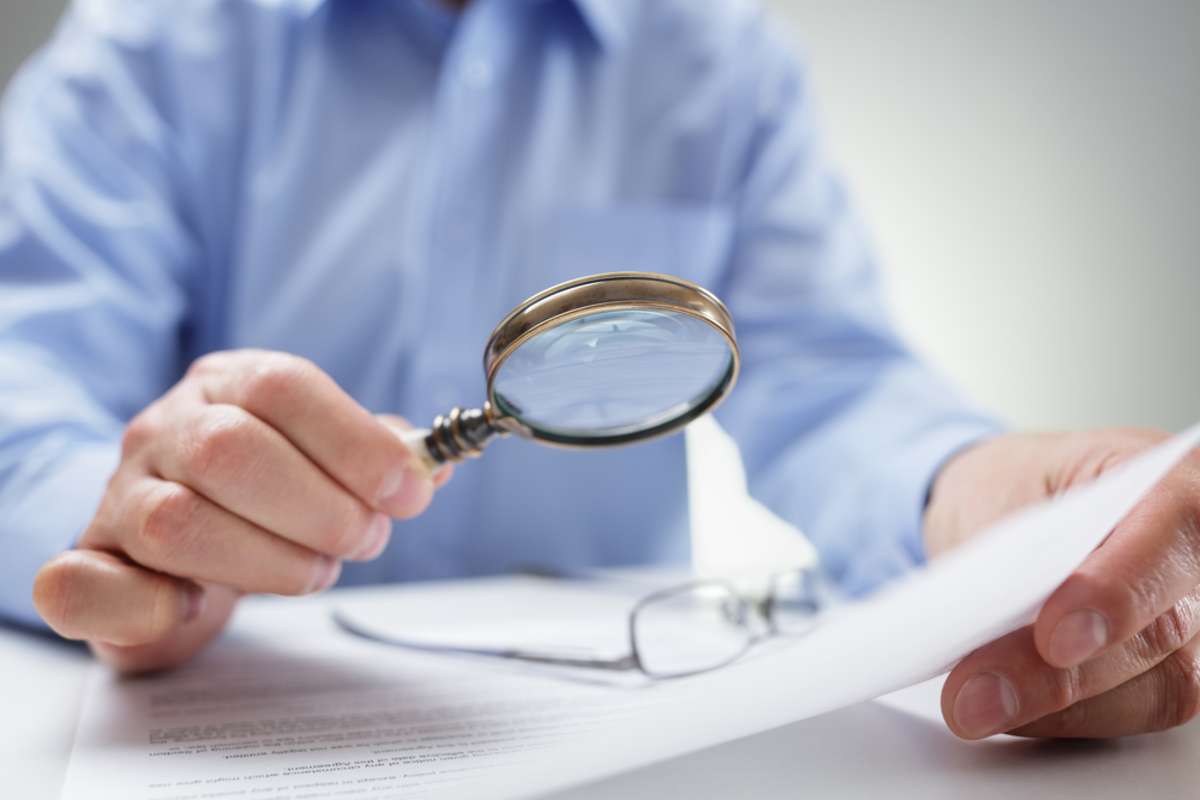 Businessman reading documents with magnifying glass concept for analyzing a  legal contract