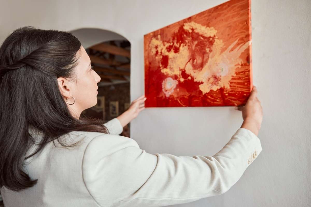 Woman hanging a painting in a home, property staging concept