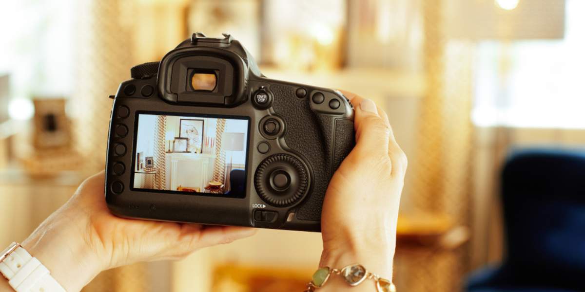 Close-up of a modern DSLR camera in the hand of a photographer, taking pictures of a home