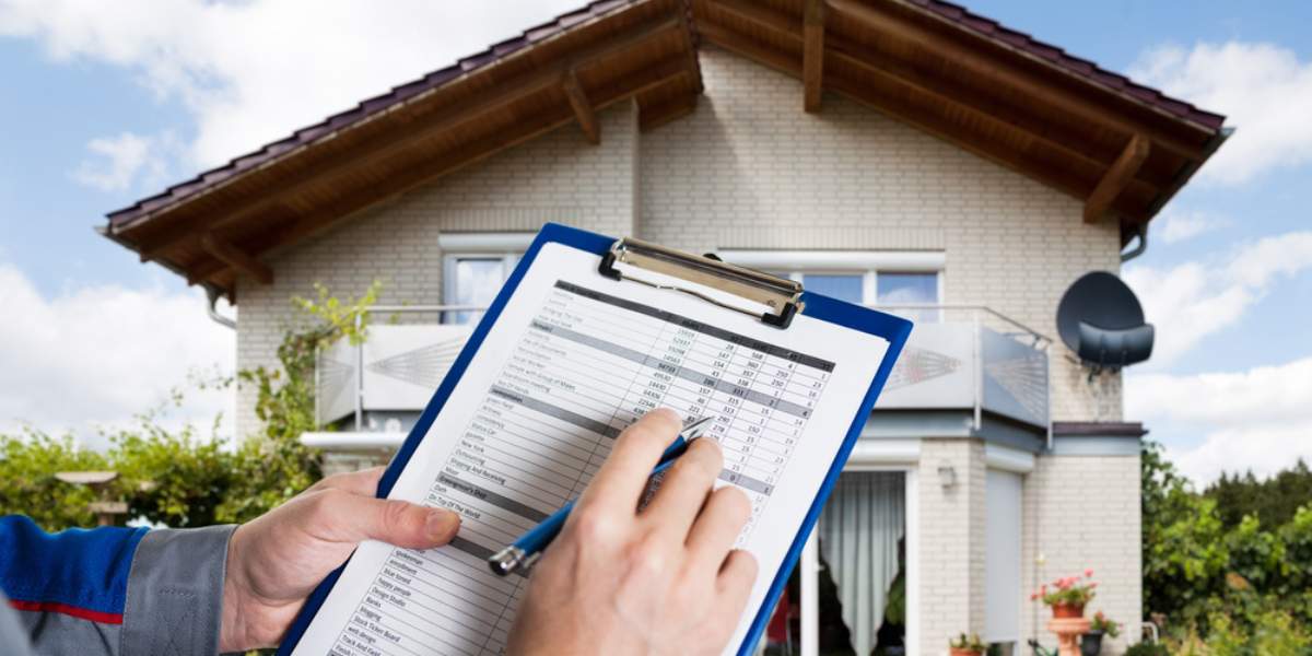 A person holding a clipboard with a property inspection checklist in front of a house